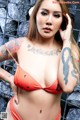 A woman in a bikini with tattoos on her arms.